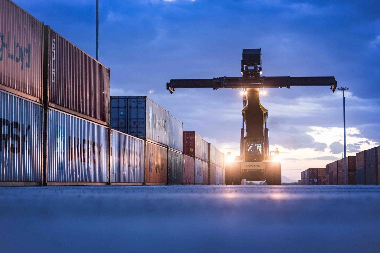 stack of containers whit a container forklift in the middle waiting for our company to transport them